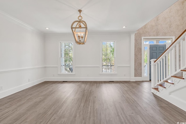 interior space with baseboards, stairway, ornamental molding, wood finished floors, and an inviting chandelier