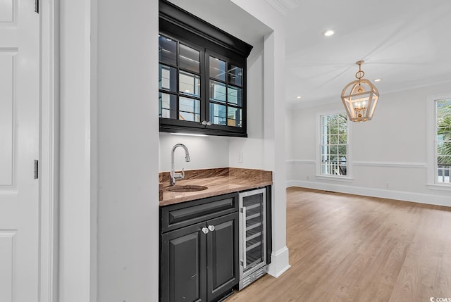 bar featuring wine cooler, indoor wet bar, light wood-style flooring, ornamental molding, and a sink