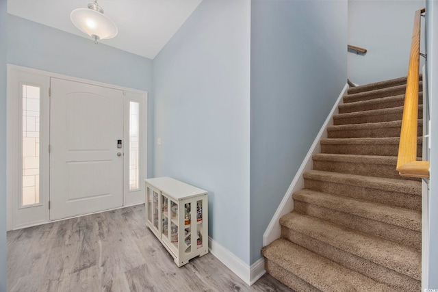 foyer entrance featuring a wealth of natural light, light wood-style flooring, baseboards, and stairs