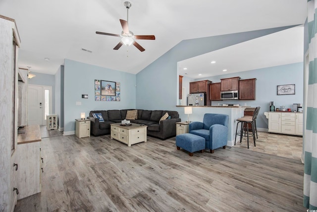 living area featuring lofted ceiling, light wood-style floors, baseboards, and recessed lighting