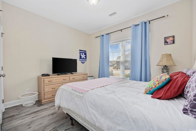 bedroom featuring light wood finished floors, visible vents, and baseboards