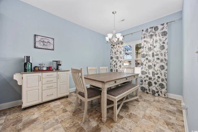 dining room with a chandelier, stone finish floor, and baseboards