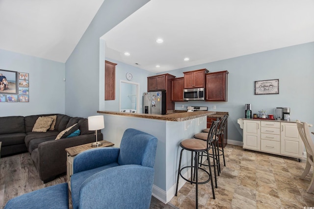 kitchen featuring a breakfast bar area, recessed lighting, appliances with stainless steel finishes, open floor plan, and baseboards