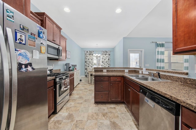 kitchen featuring dark countertops, a peninsula, stainless steel appliances, a chandelier, and a sink