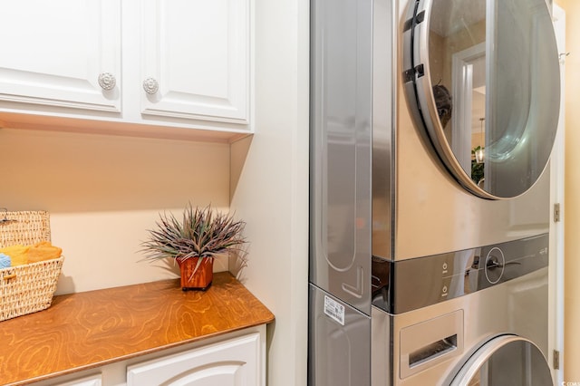 laundry area with stacked washer and dryer and cabinet space