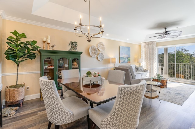 dining space with ceiling fan with notable chandelier, a raised ceiling, crown molding, and wood finished floors