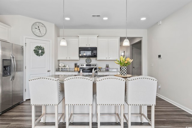 kitchen featuring stainless steel appliances, white cabinets, dark wood-type flooring, and a kitchen bar