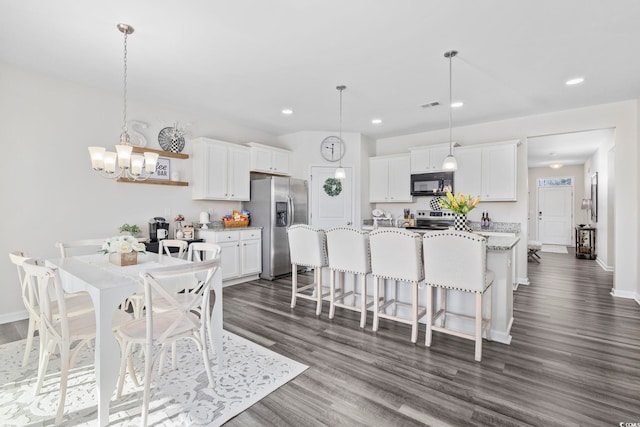 kitchen featuring white cabinetry, a breakfast bar area, stainless steel appliances, and dark wood-type flooring