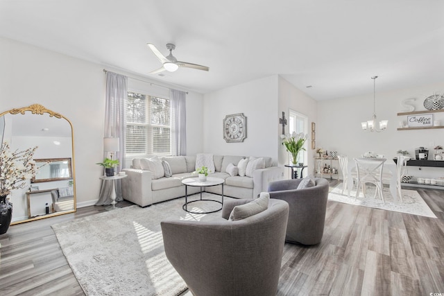 living room featuring baseboards, wood finished floors, and ceiling fan with notable chandelier