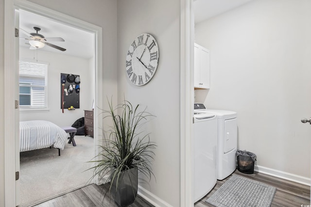 laundry room featuring ceiling fan, washing machine and dryer, wood finished floors, baseboards, and cabinet space