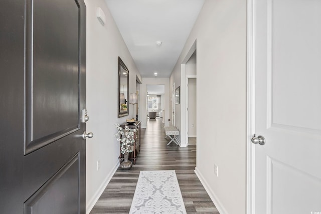 hall with dark wood-style flooring and baseboards