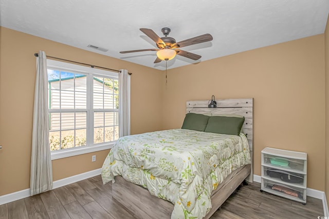 bedroom with visible vents, ceiling fan, baseboards, and wood finished floors