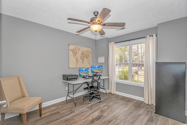 office space with visible vents, a textured ceiling, baseboards, and wood finished floors