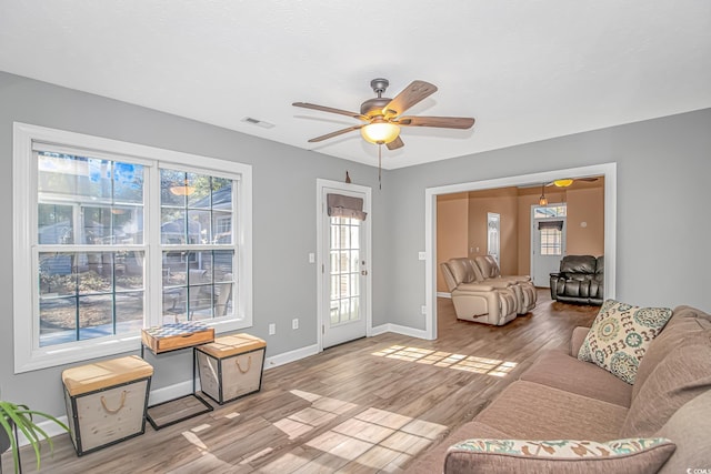 living area featuring ceiling fan, wood finished floors, visible vents, and baseboards