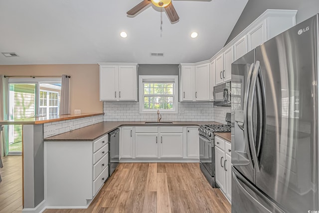 kitchen featuring stainless steel appliances, visible vents, a sink, and a peninsula