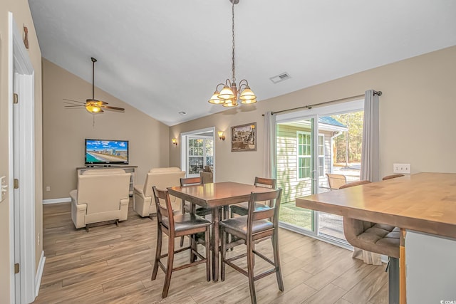 dining room featuring visible vents, baseboards, light wood-style flooring, vaulted ceiling, and ceiling fan with notable chandelier