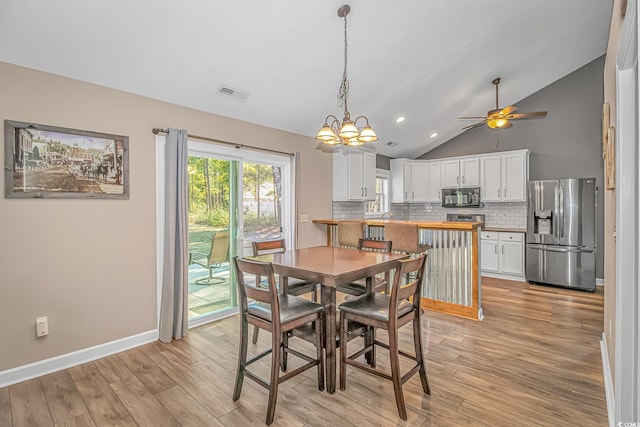 dining space featuring light wood-style floors, lofted ceiling, visible vents, and baseboards