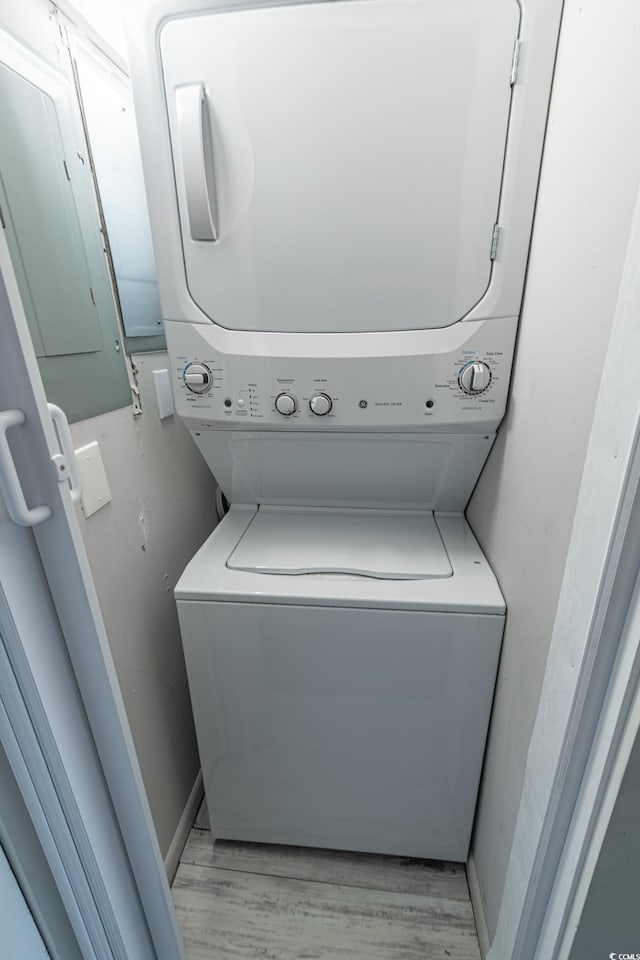 laundry room featuring light wood-style floors, stacked washer and clothes dryer, and laundry area