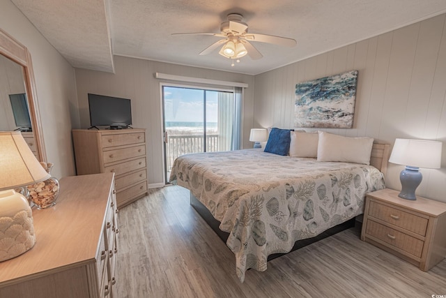 bedroom with light wood finished floors, access to outside, ceiling fan, and a textured ceiling