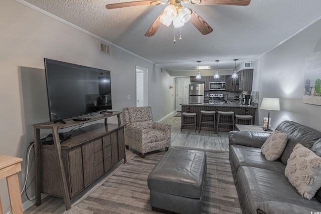 living room featuring visible vents, crown molding, a textured ceiling, and ceiling fan