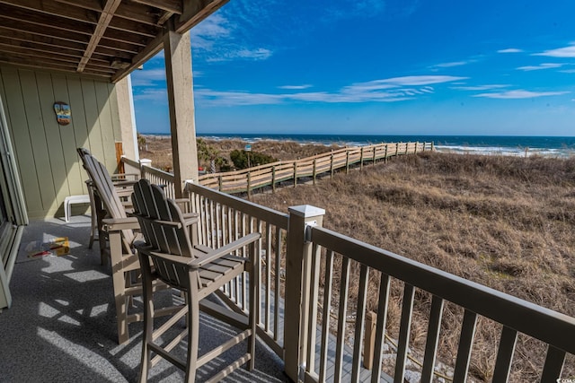 balcony with a water view and a view of the beach