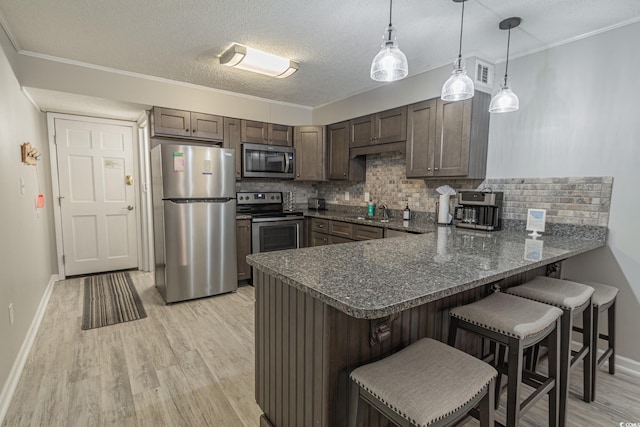 kitchen featuring tasteful backsplash, visible vents, appliances with stainless steel finishes, light wood-type flooring, and a peninsula