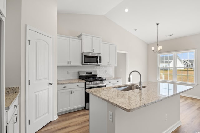 kitchen featuring light wood-style flooring, a sink, vaulted ceiling, stainless steel appliances, and backsplash