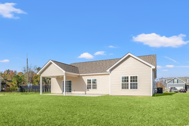 rear view of house with a patio area, a shingled roof, and a yard