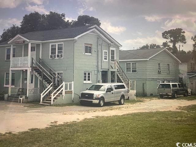 rear view of property featuring a lawn and stairway