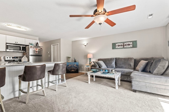 living area featuring ceiling fan, light colored carpet, visible vents, and baseboards