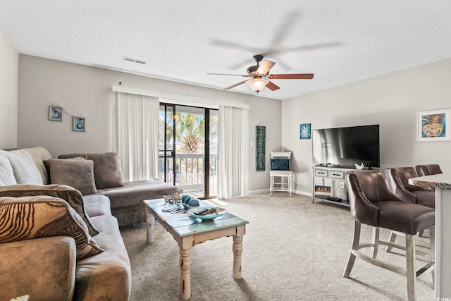 carpeted living room with a ceiling fan, visible vents, a textured ceiling, and baseboards