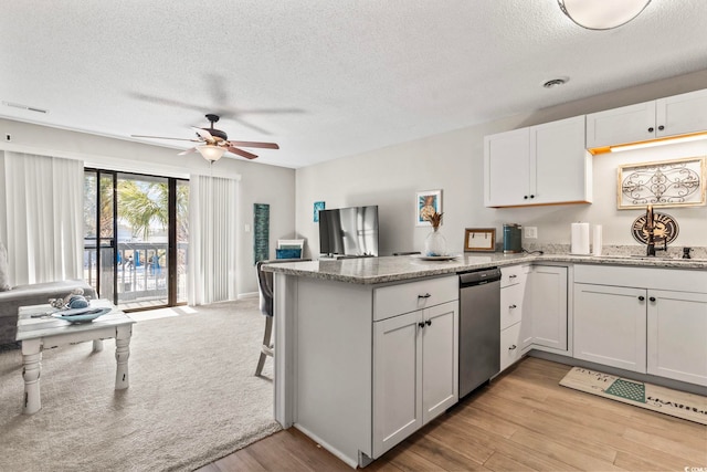 kitchen with a peninsula, light wood-style flooring, visible vents, and white cabinetry