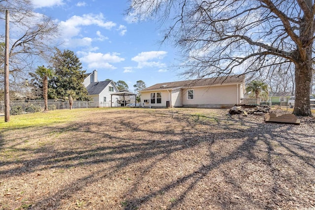 back of property featuring a yard, fence, and a gazebo