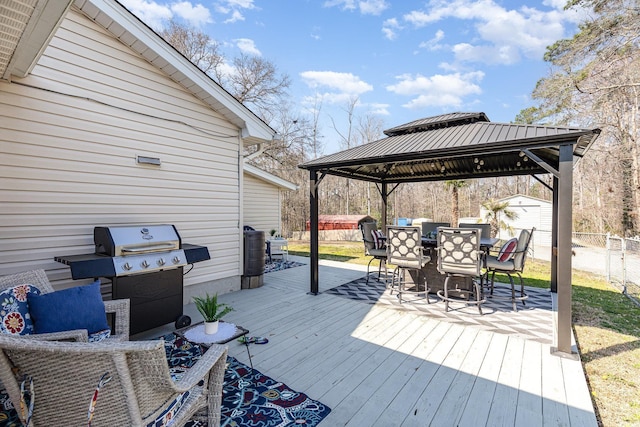 wooden deck with an outbuilding, outdoor dining area, grilling area, a gazebo, and a shed