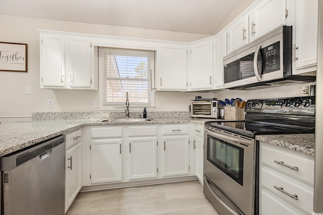 kitchen featuring appliances with stainless steel finishes, white cabinets, and a sink