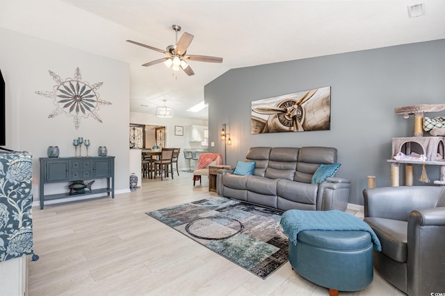 living area with lofted ceiling, ceiling fan, visible vents, baseboards, and light wood-style floors