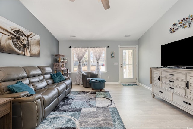 living room with ceiling fan, lofted ceiling, visible vents, baseboards, and light wood-type flooring