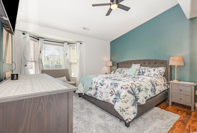 bedroom with ceiling fan, visible vents, vaulted ceiling, and wood finished floors