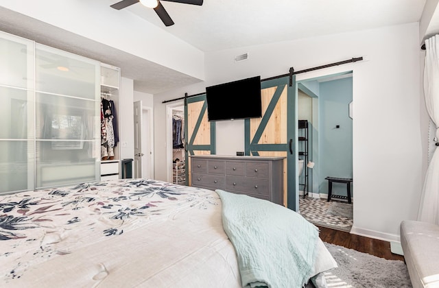 bedroom with lofted ceiling, a barn door, wood finished floors, a spacious closet, and a closet