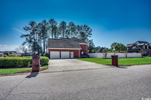 view of front of home featuring a garage, driveway, fence, a front yard, and brick siding