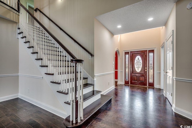 foyer entrance featuring baseboards, arched walkways, hardwood / wood-style floors, a high ceiling, and recessed lighting