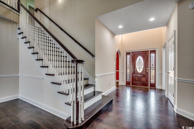 foyer with stairs, arched walkways, baseboards, and wood finished floors