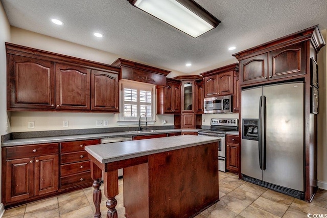 kitchen with appliances with stainless steel finishes, a sink, a textured ceiling, a center island, and recessed lighting