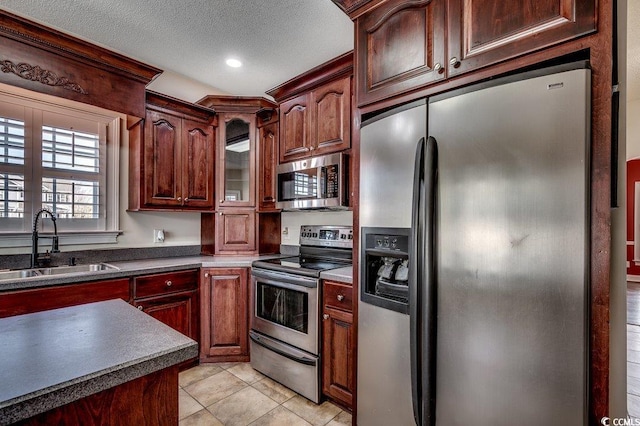 kitchen with dark countertops, a sink, light tile patterned floors, stainless steel appliances, and recessed lighting