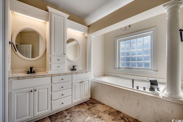 bathroom with a sink, double vanity, decorative columns, and a bath