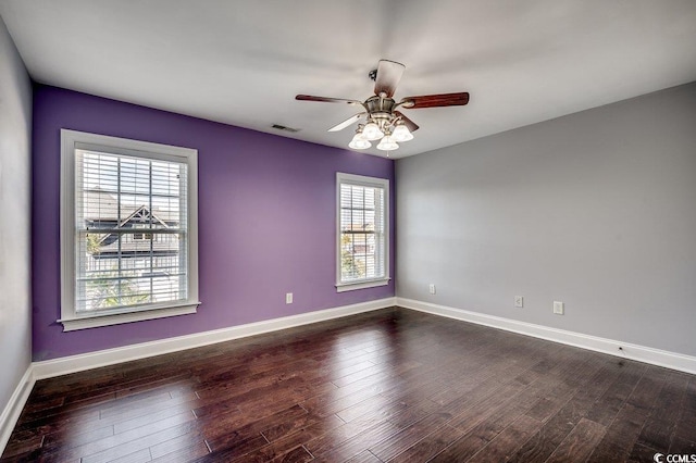 empty room with visible vents, baseboards, and dark wood finished floors