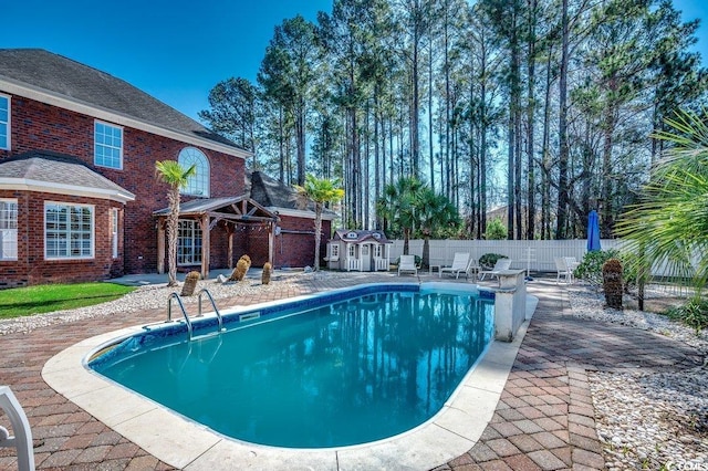 view of pool featuring a storage shed, an outbuilding, a fenced in pool, a fenced backyard, and a patio