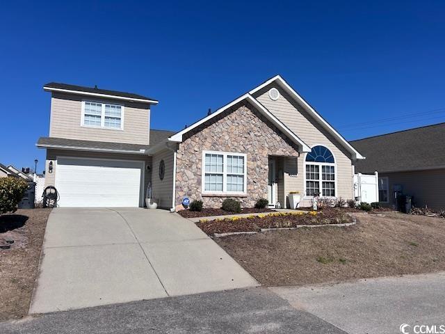 ranch-style home featuring an attached garage, stone siding, and driveway