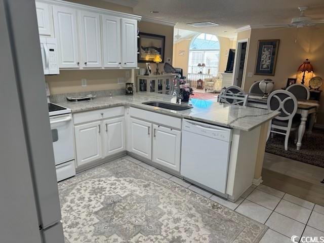 kitchen featuring open floor plan, a peninsula, white appliances, white cabinetry, and a sink