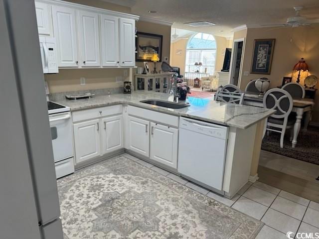 kitchen featuring open floor plan, white appliances, a peninsula, crown molding, and a sink
